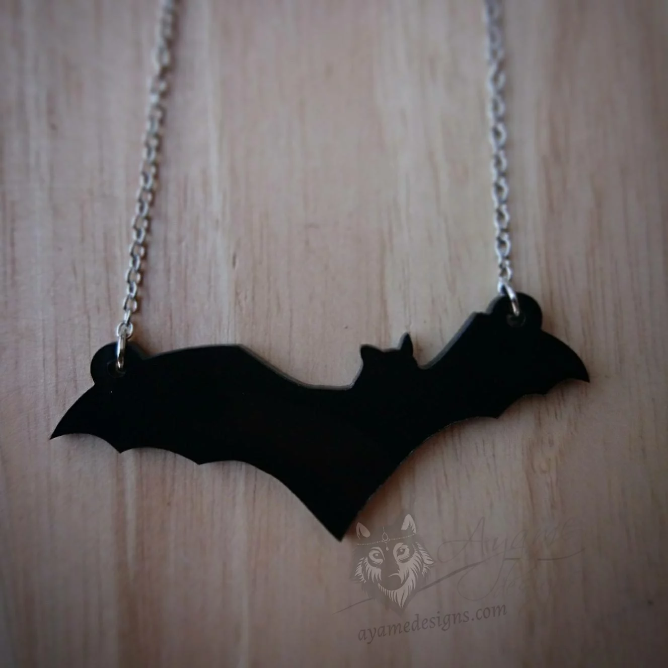 A laser cut perspex bat pendant on a stainless steel adjustable chain