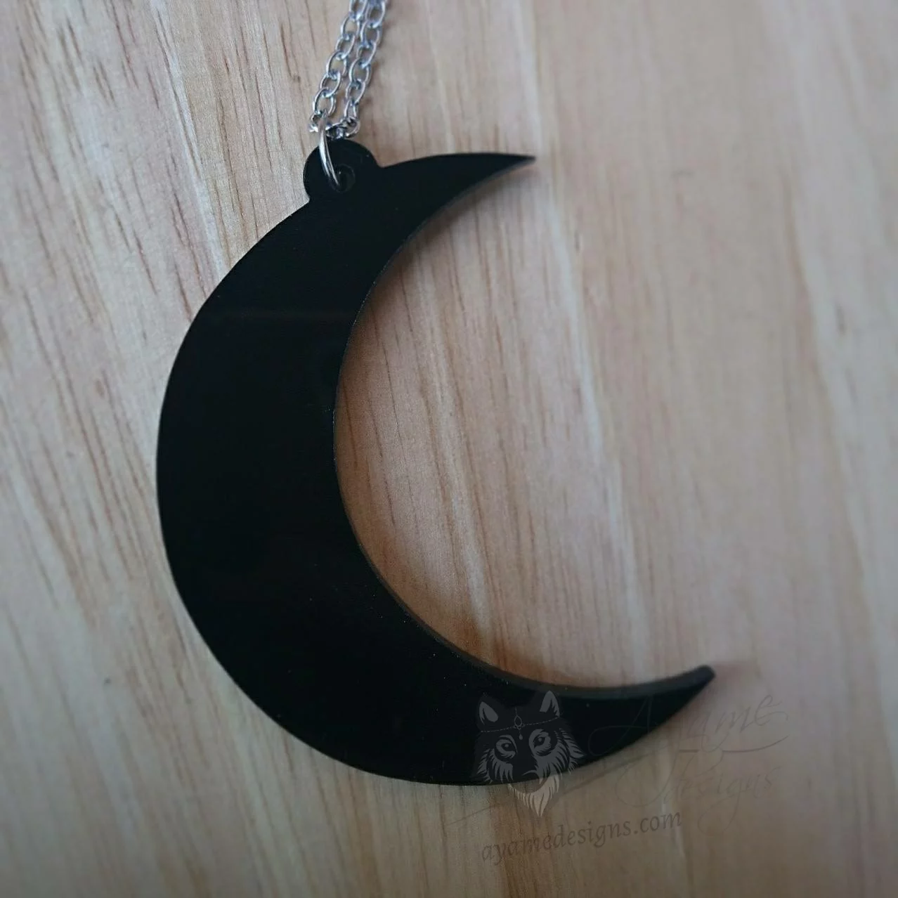 A laser cut perspex crescent moon pendant on a stainless steel adjustable chain