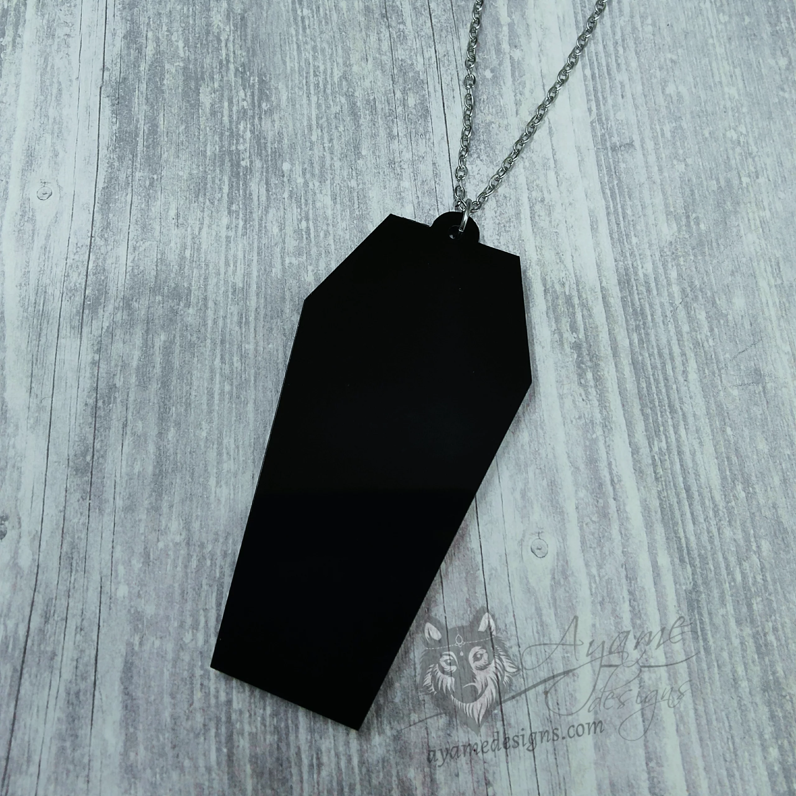 A laser cut perspex coffin pendant on a stainless steel adjustable chain