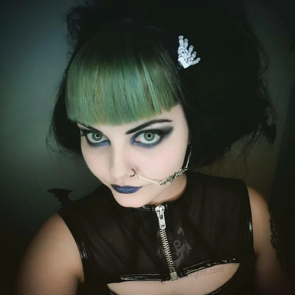A gothic female model wearing a handmade filigree bat nose to ear chain