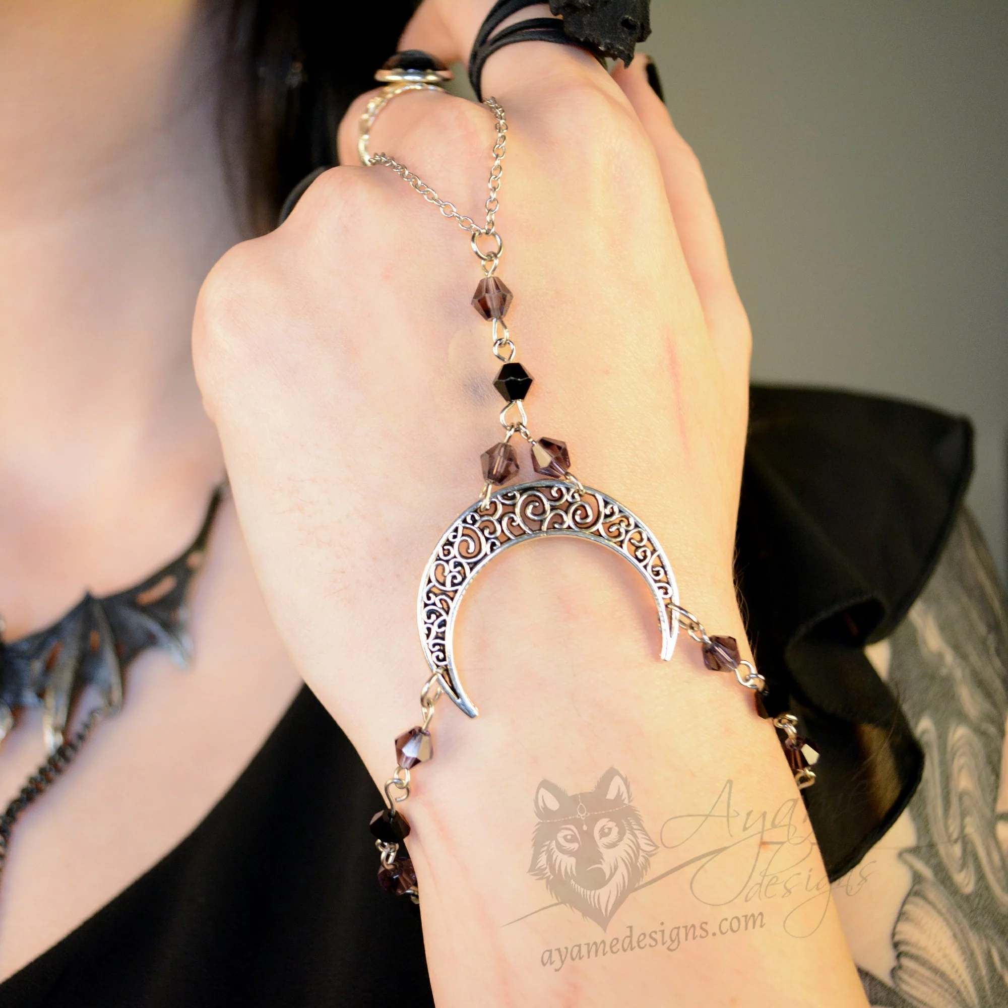 Handmade gothic hand bracelet with a filigree moon pendant, and purple and black Austrian crystal beads