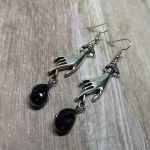 Elegant gothic earrings with hand charms and purple teardrop charms, on stainless steel earring hooks