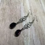 Elegant gothic earrings with filigree connectors and purple teardrop charms, on stainless steel earring hooks