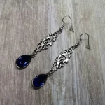 Elegant gothic earrings with filigree connectors and blue teardrop charms, on stainless steel earring hooks