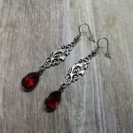 Elegant gothic earrings with filigree connectors and red teardrop charms, on stainless steel earring hooks