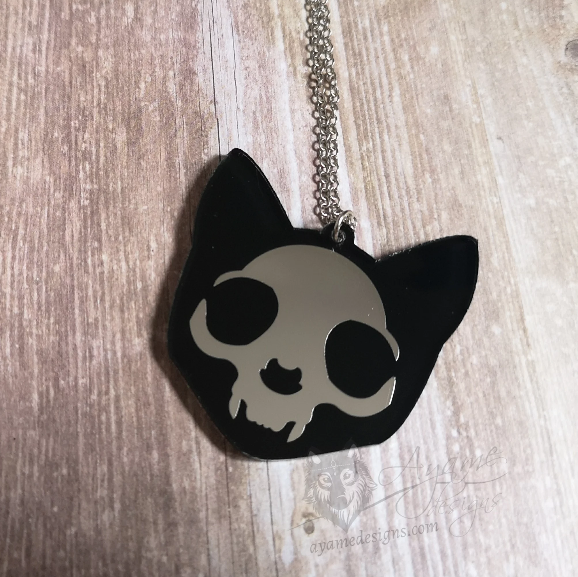 A laser cut mirror and resin cat skull pendant on a stainless steel adjustable chain