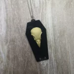 A simple gothic necklace with a resin bird skull on a black perspex coffin, on a silver stainless steel chain
