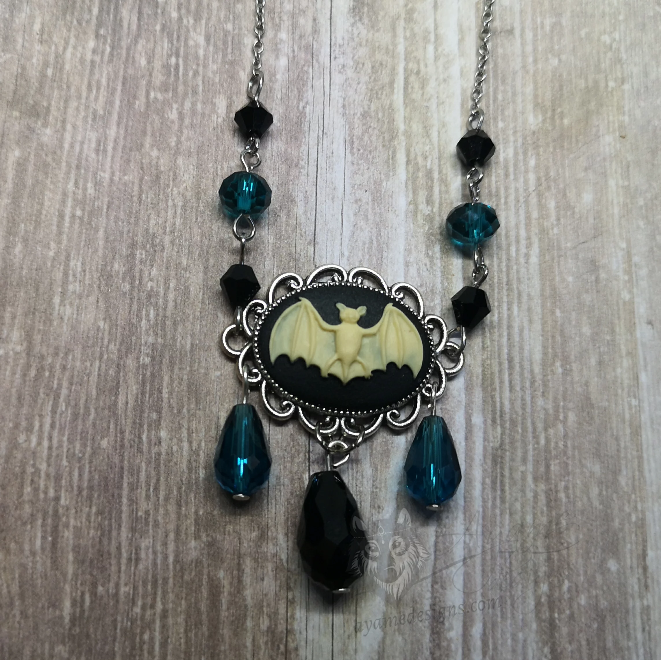 Adjustable gothic necklace with a bat cameo in a filigree frame, with black and teal Austrian crystal beads and stainless steel chain