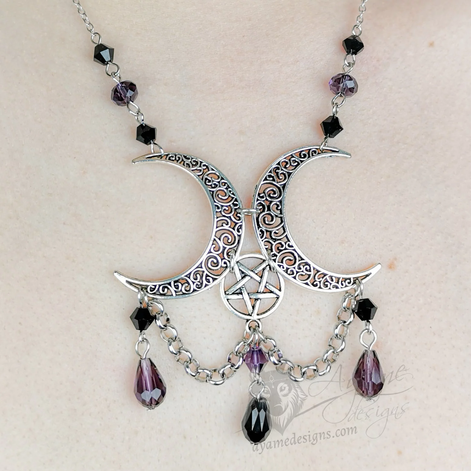 Handmade pagan triple moon necklace with filigree moons, an inverted pentacle, black and purple Austrian crystal beads, and stainless steel chain details