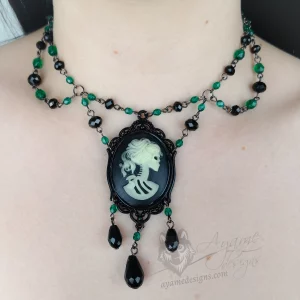 handmade adjustable Victorian gothic choker necklace with green Czech crystal and black Austrian crystal beads, and a glow in the dark skeleton cameo pendant in a black filigree frame
