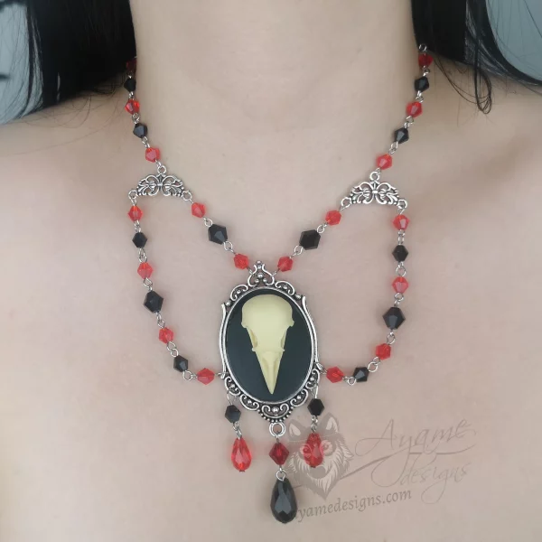 Handmade beaded choker necklace with a large resin bird skull pendant in a filigree frame, and red and black Austrian crystal beads