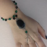 Handmade gothic hand bracelet with a black resin cabochon in a filigree frame, and green Czech crystal and black Austrian crystal beads