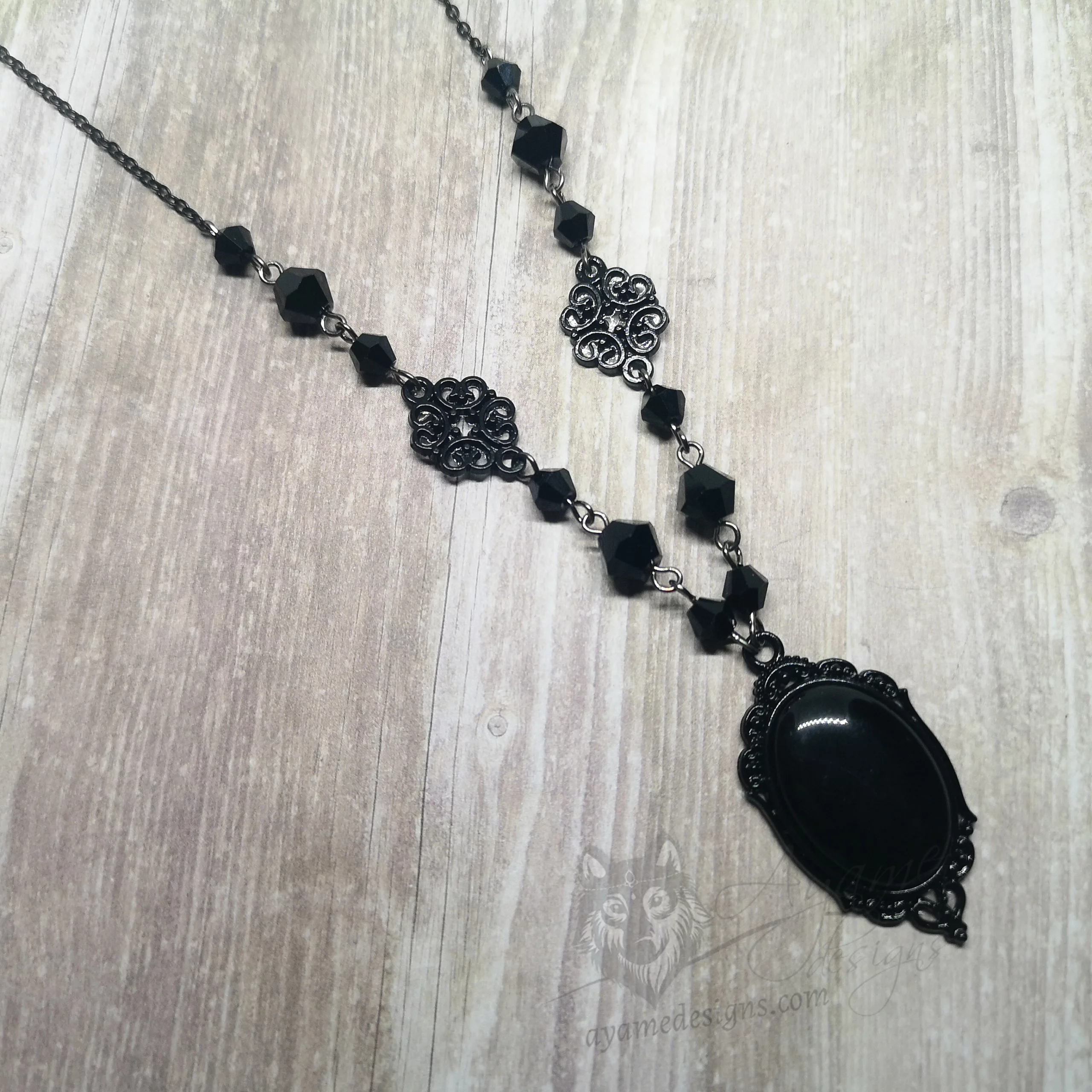 Handmade gothic necklace with a small black resin cabochon in a black filigree frame, black Austrian crystal beads and black stainless steel chain