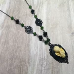 Handmade gothic necklace with a small resin bat skull in a black filigree frame, green and black Austrian crystal beads and black stainless steel chain