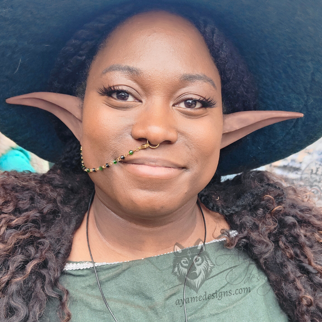 Woman cosplaying an elf wearing a handmade gold nose to ear chain with black and green Austrian crystal beads
