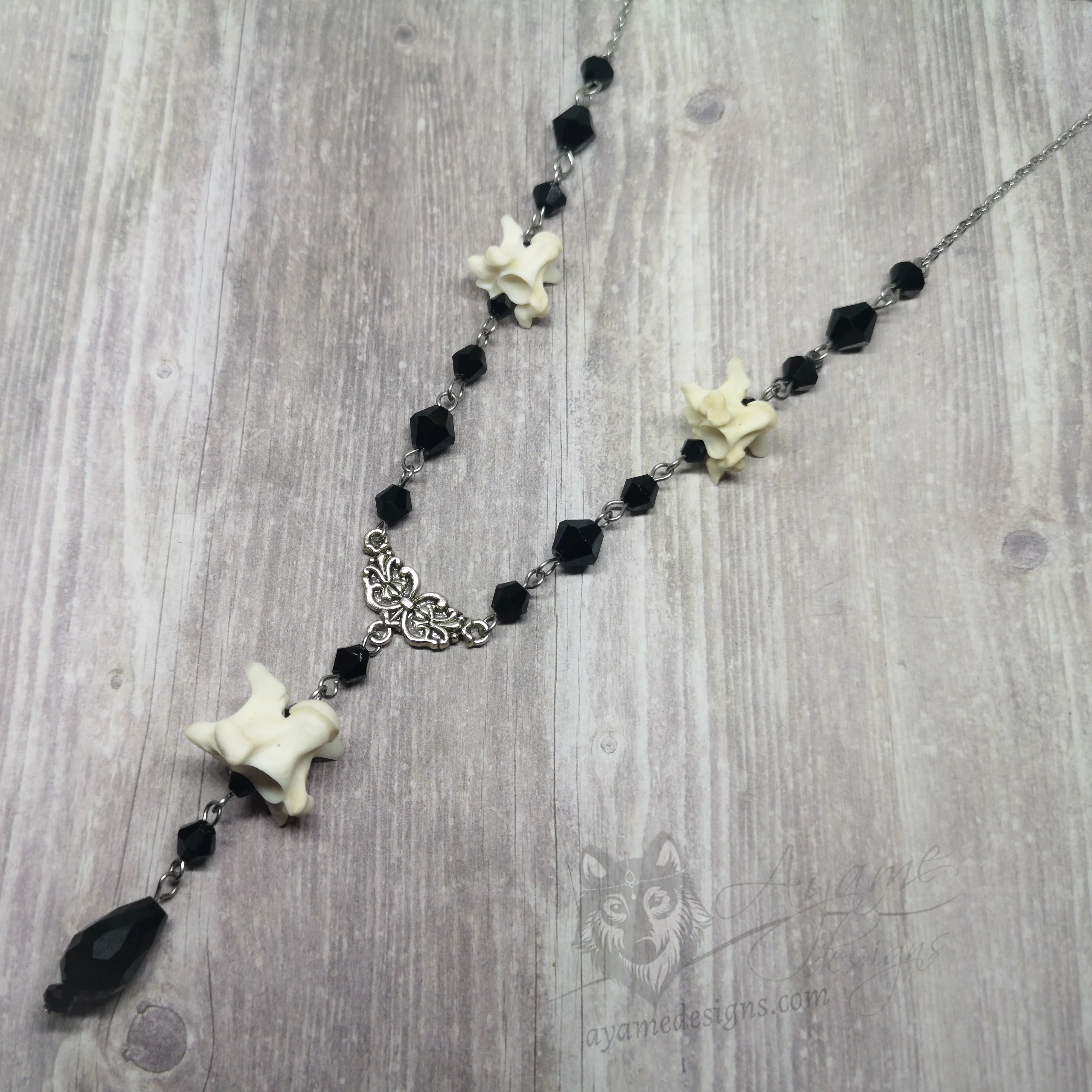 Handmade adjustable necklace with snake vertebrae, a filigree connector, black Austrian crystal beads, and stainless steel chain