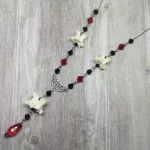 Handmade adjustable necklace with snake vertebrae, a filigree connector, black and red Austrian crystal beads, and stainless steel chain