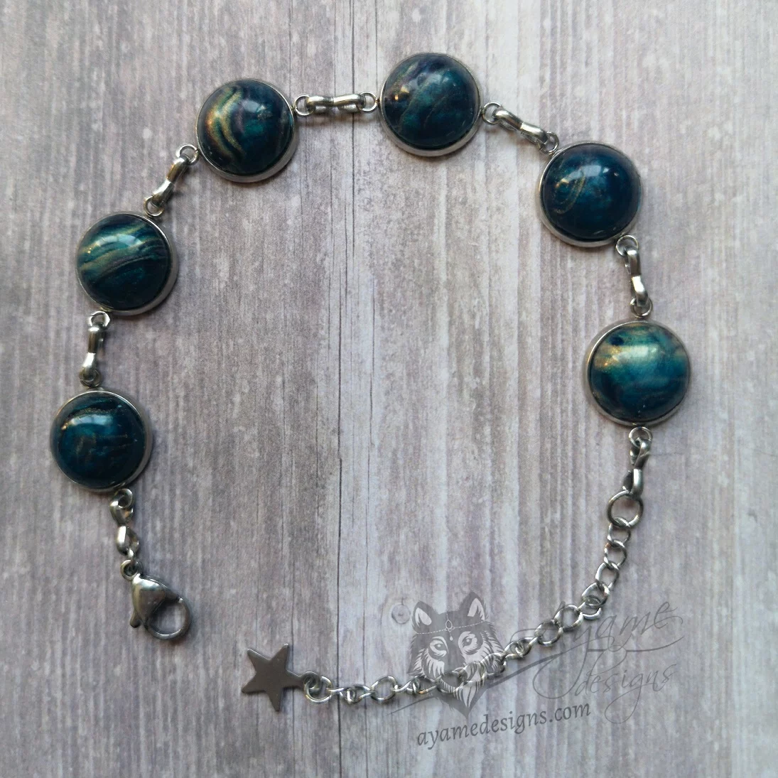 Adjustable stainless steel bracelet with small blue and gold galaxy swirl resin cabochons