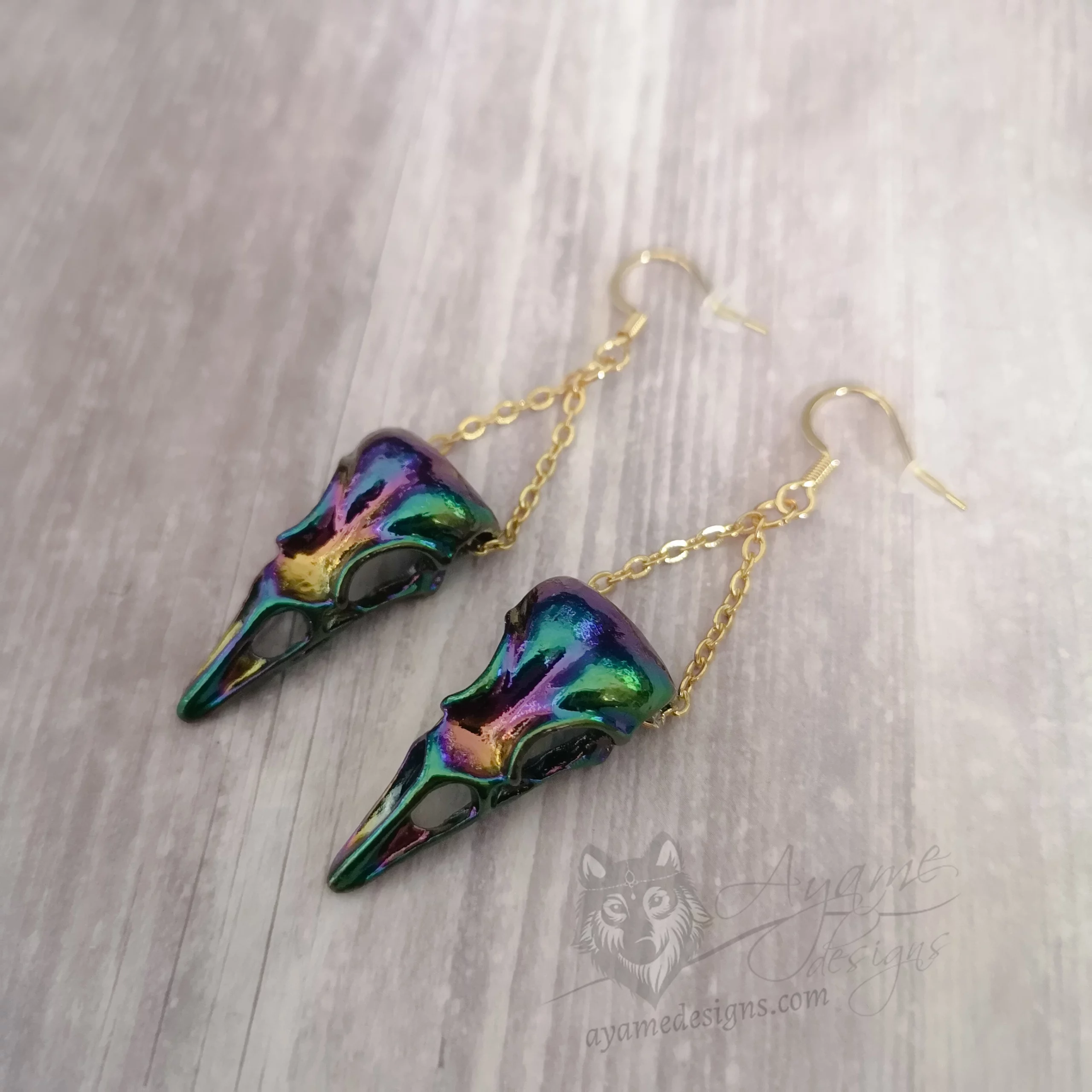 Earrings with rainbow bird skull pendants hanging on gold stainless steel chain, on gold stainless steel earring hooks