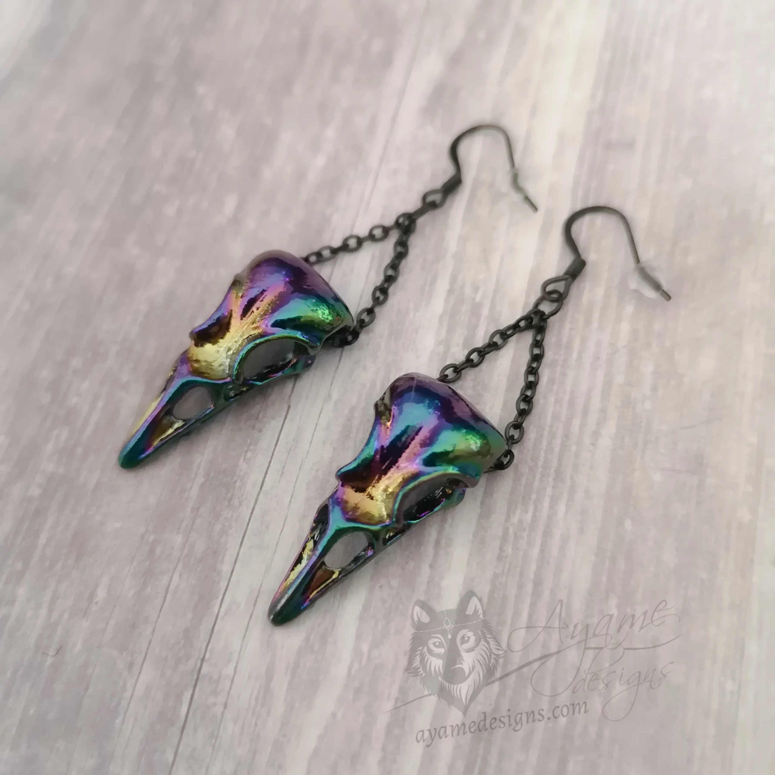 Earrings with rainbow bird skull pendants hanging on black stainless steel chain, on black stainless steel earring hooks