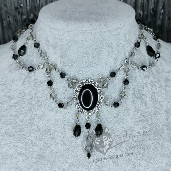 An adjustable gothic beaded choker necklace with black and grey Austrian crystal beads and a black resin cabochon inside a silver filigree frame