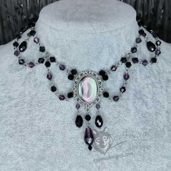 An adjustable gothic beaded choker necklace with black and purple Austrian crystal beads and a purple and silver swirl resin cabochon inside a silver filigree frame