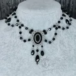 An adjustable gothic beaded choker necklace with black Austrian crystal beads and a black resin cabochon inside a silver filigree frame