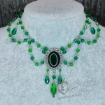An adjustable gothic beaded choker necklace with light green Austrian crystal beads and a dark green resin cabochon inside a silver filigree frame