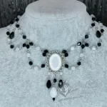 An adjustable gothic beaded choker necklace with black and white Austrian crystal beads and a white resin cabochon inside a silver filigree frame