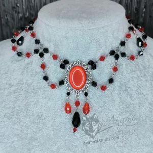 An adjustable gothic beaded choker necklace with black and red Austrian crystal beads and a red resin cabochon inside a silver filigree frame