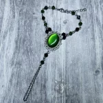Handmade gothic bracelet with a green resin cabochon in a filigree frame, and black and green Austrian crystal beads
