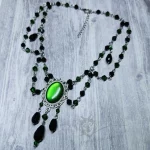 An adjustable gothic beaded choker necklace with black and green Austrian crystal beads and a green resin cabochon inside a silver filigree frame