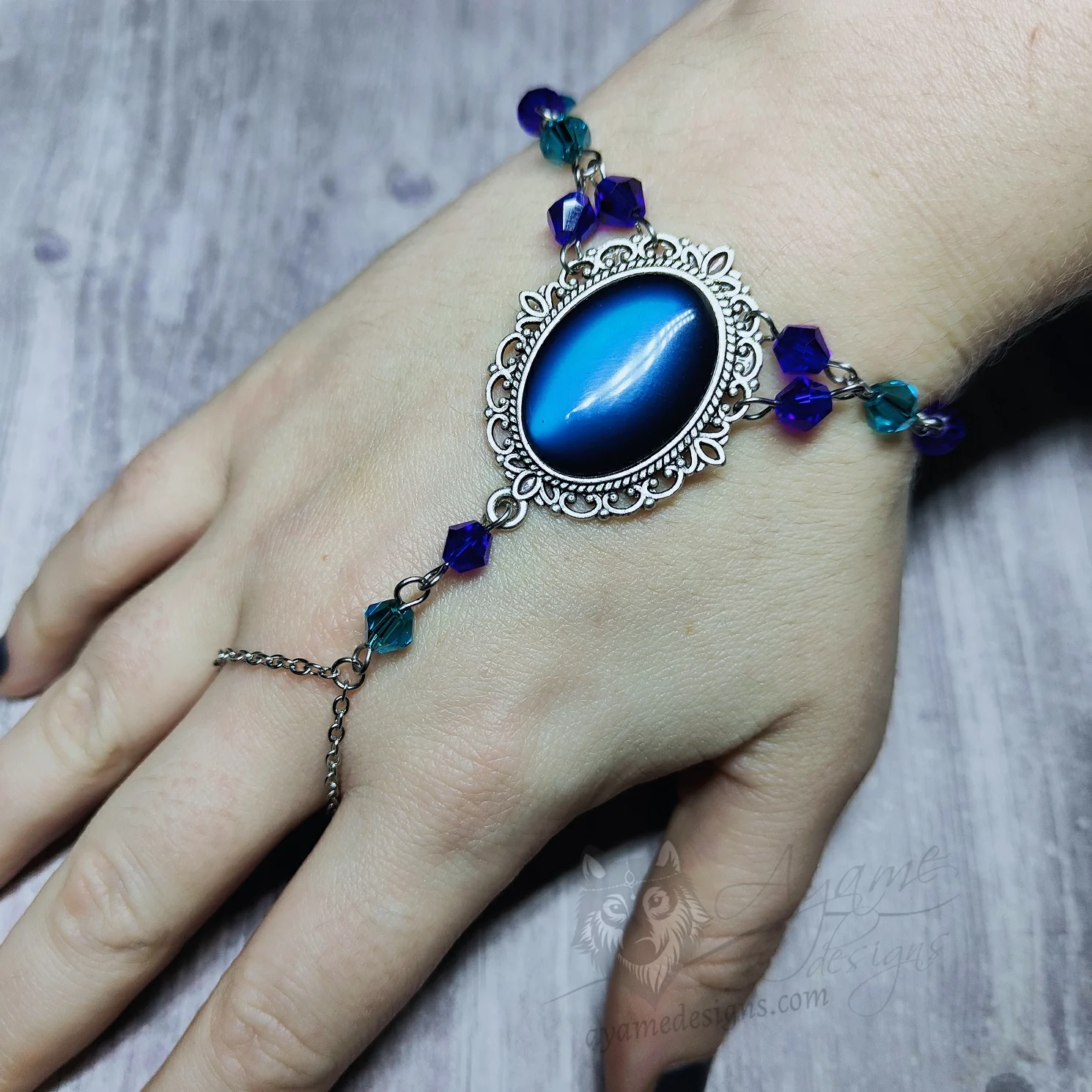 Handmade gothic bracelet with a blue resin cabochon in a filigree frame, and blue Austrian crystal beads