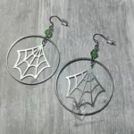 Handmade earrings with laser cut stainless steel spider web charms inside large stainless steel rings with light green Austrian crystal beads, on stainless steel earring hooks