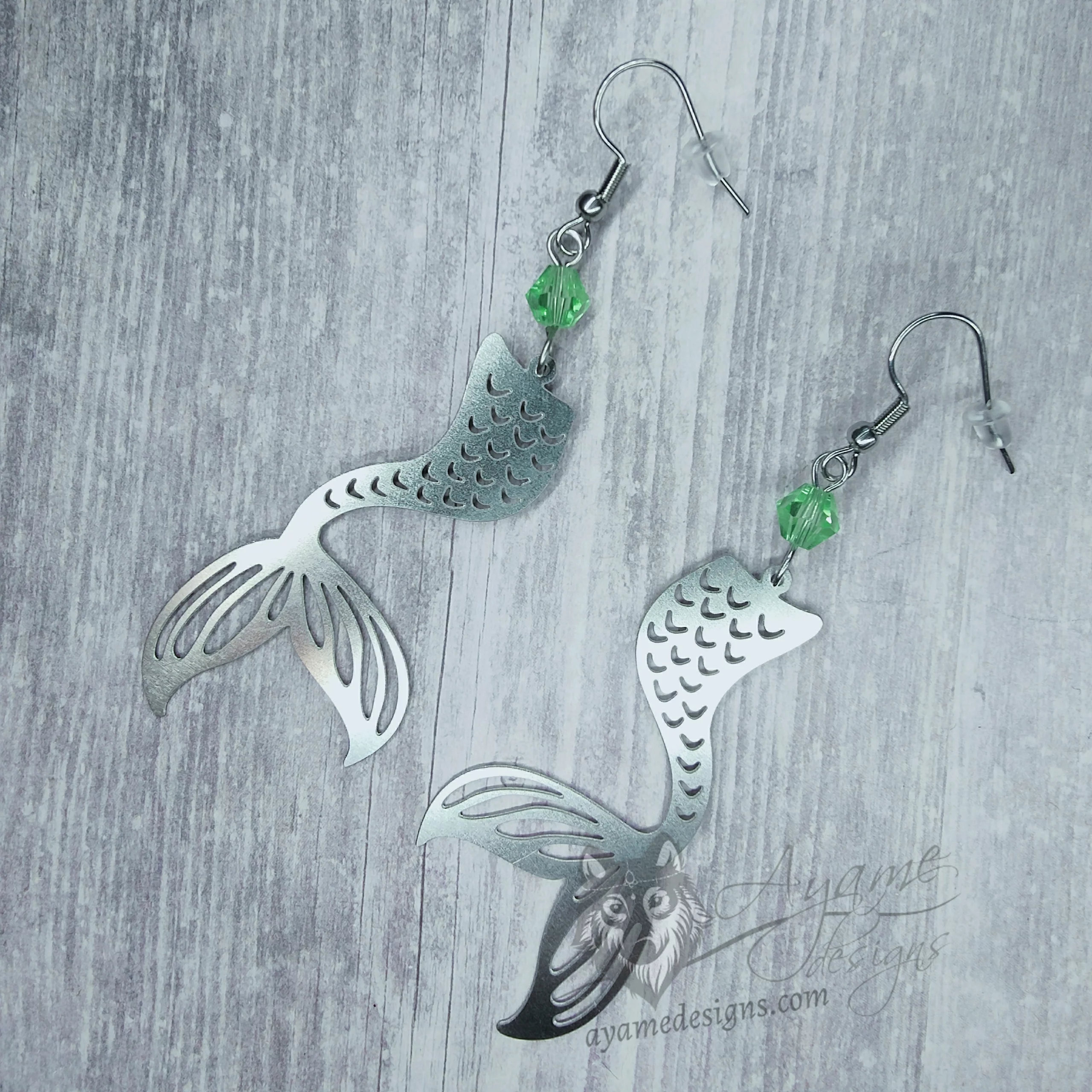 Handmade earrings with laser cut stainless steel mermaid tail charms with light green Austrian crystal beads, on stainless steel earring hooks