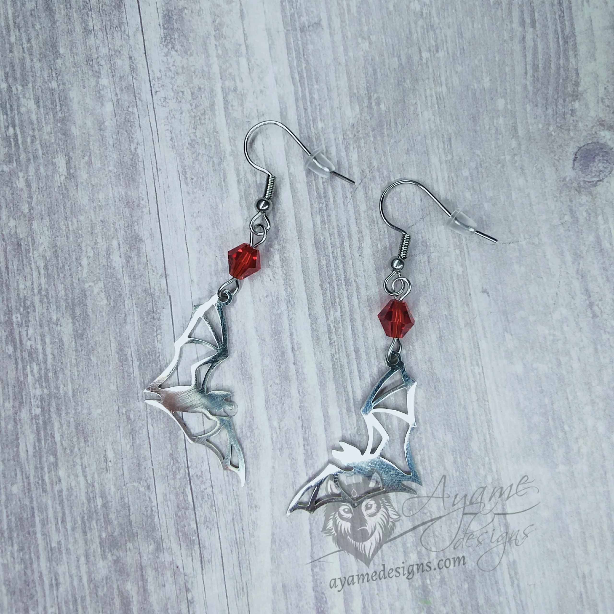 Handmade earrings with laser cut stainless steel bat charms with red Austrian crystal beads, on stainless steel earring hooks
