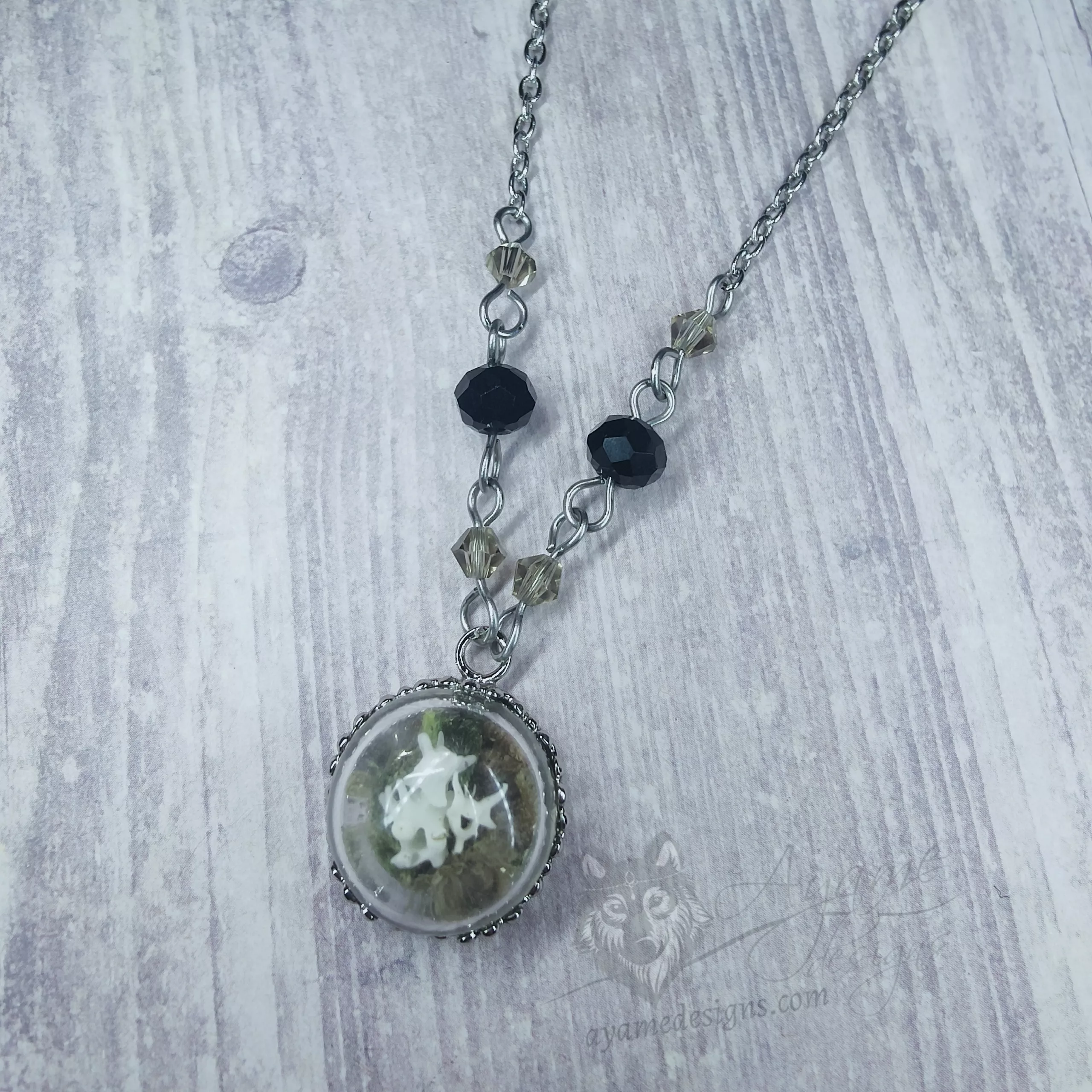 Glass dome necklace with ethically sourced snake vertebrae and moss, grey and black Austrian crystal beads and stainless steel chain