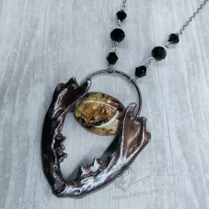 A necklace made with real ferret jaw bones and resin plated (electroformed) in copper with a gunmetal finish and black Austrian crystal beads, on a stainless steel chain