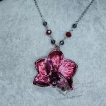 A necklace made with a real orchid plated (electroformed) in copper with a bright pink, red and purple finish, on a stainless steel chain