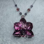 A necklace made with a real orchid plated (electroformed) in copper with a pale pink and purple finish, on a stainless steel chain