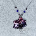 A necklace with a real orchid flower that has been plated with copper, finished with dark purple and blue inks