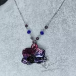 A necklace with a real orchid flower that has been plated with copper, finished with dark purple and blue inks