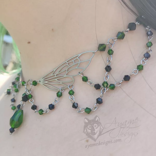 An adjustable cottagecore fairycore fantasy beaded choker necklace with green and black Austrian crystal beads and stainless steel laser cut fairy wings