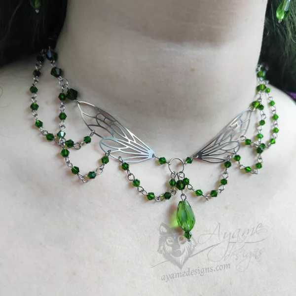 An adjustable cottagecore fairycore fantasy beaded choker necklace with green Austrian crystal beads and stainless steel laser cut fairy wings